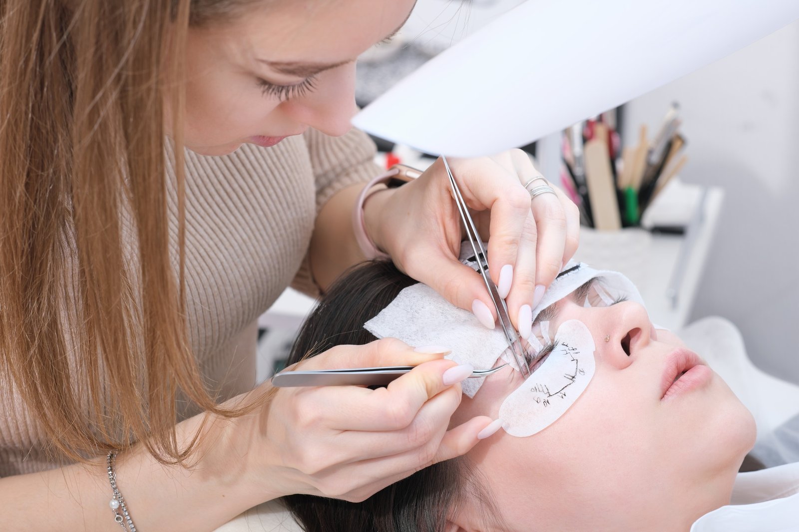 Master applies lash dye to eyelashes. Close-up of beauty model's face during lash extension